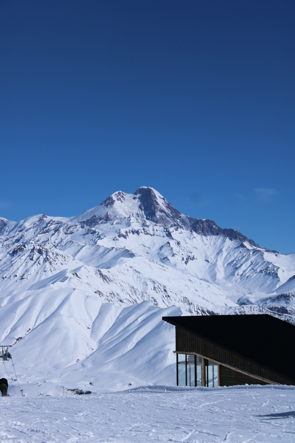 brown wooden house on snow covered mountain during daytime