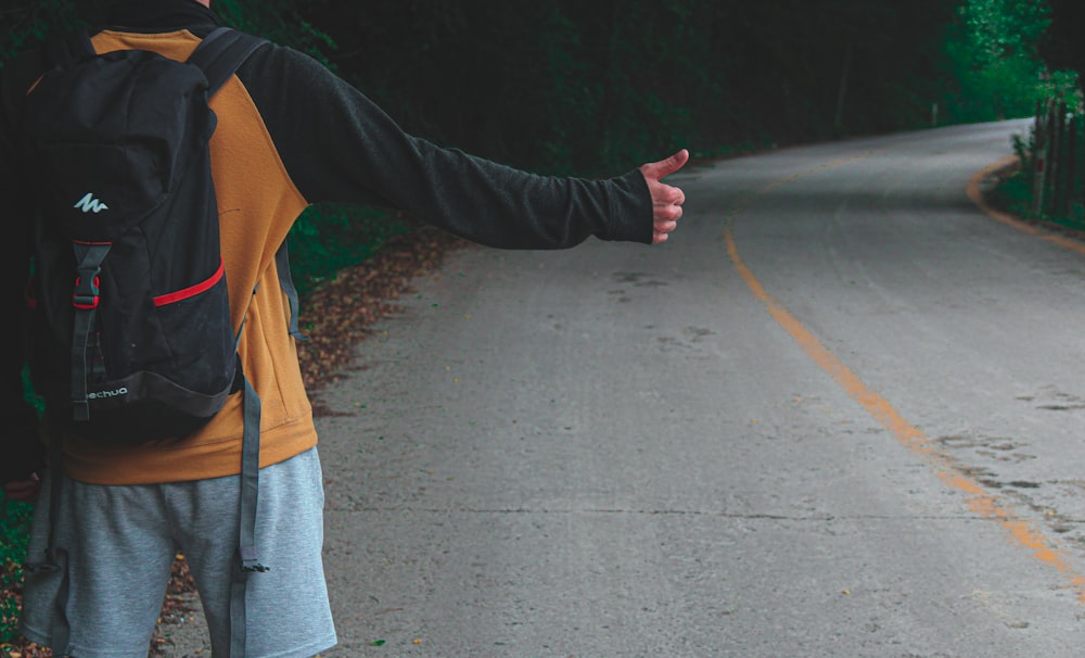 Femme en veste marron et pantalon gris marchant sur une route asphaltée grise pendant la journée