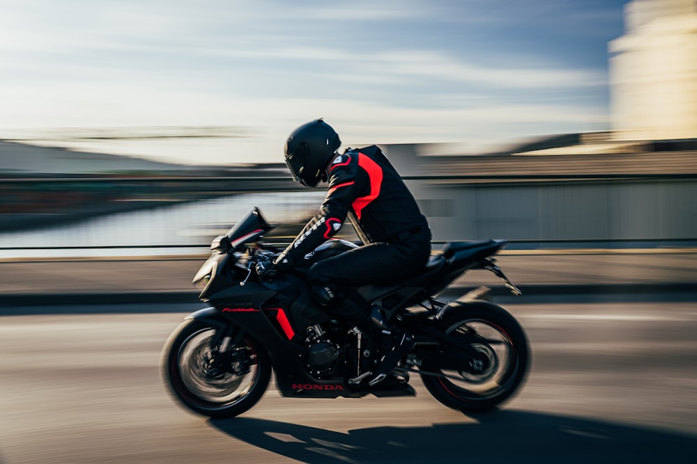 昼間、道路で黒いスポーツバイクに乗る黒いヘルメットをかぶった男