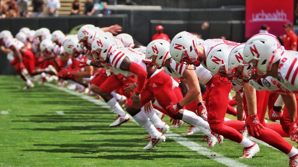 football players in red and white uniform on green field during daytime