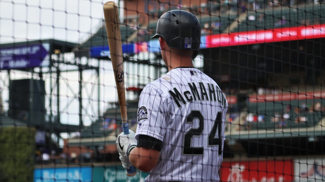 man in white and black baseball jersey shirt and black baseball helmet holding baseball bat