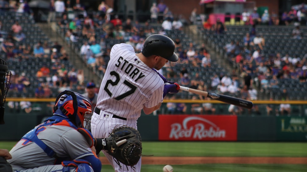 man in white and black baseball jersey holding baseball bat