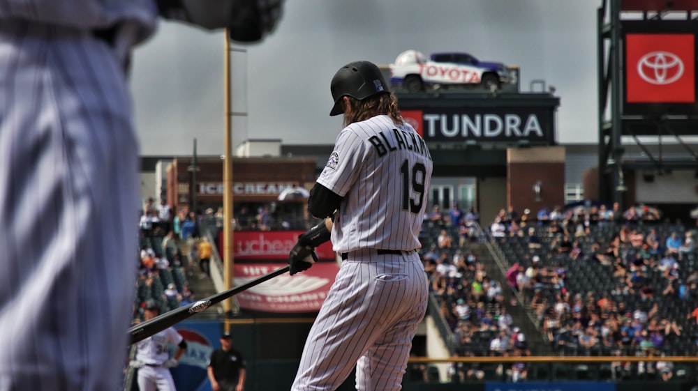 man in white jersey shirt and white pants holding baseball bat