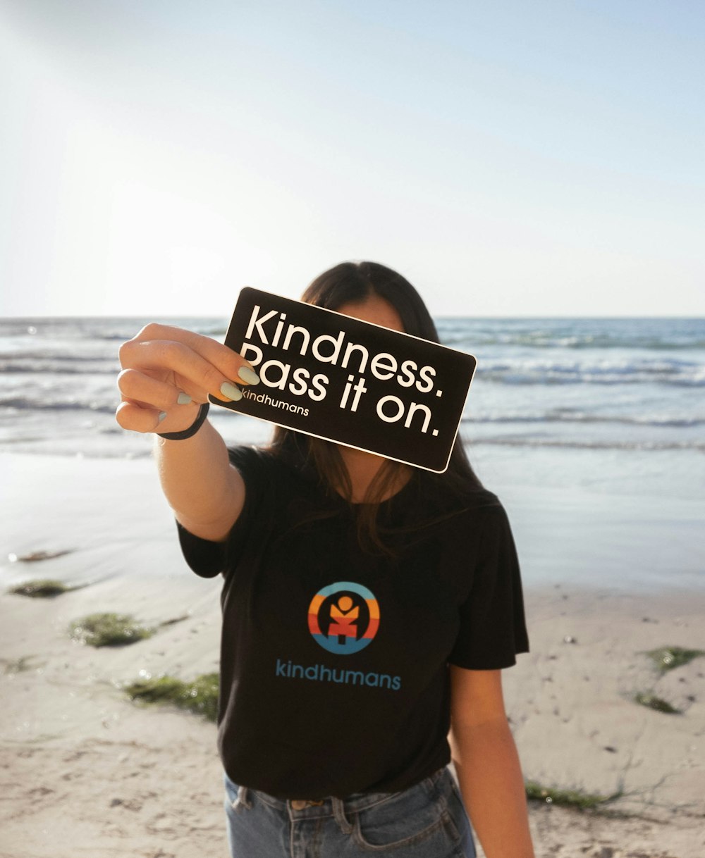 a woman holding up a sign on the beach