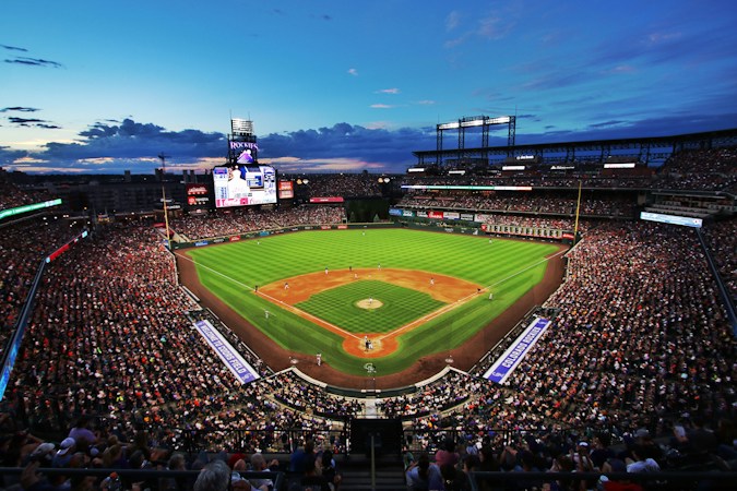 A crowd watching a baseball game under the lights at night, like a spring evening game at Las Vegas Ballpark in Downtown Summerlin
