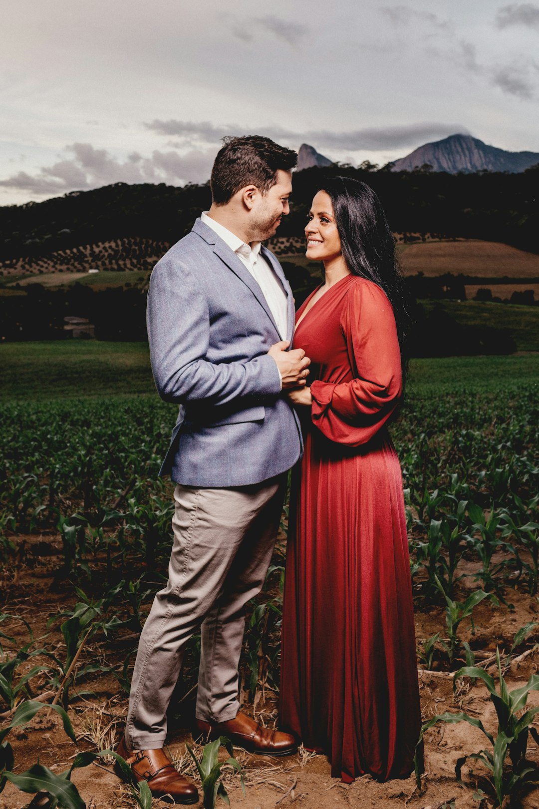 man in gray suit jacket and woman in red dress standing on green grass field during