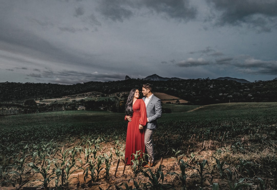 man and woman standing on brown grass field near body of water during daytime