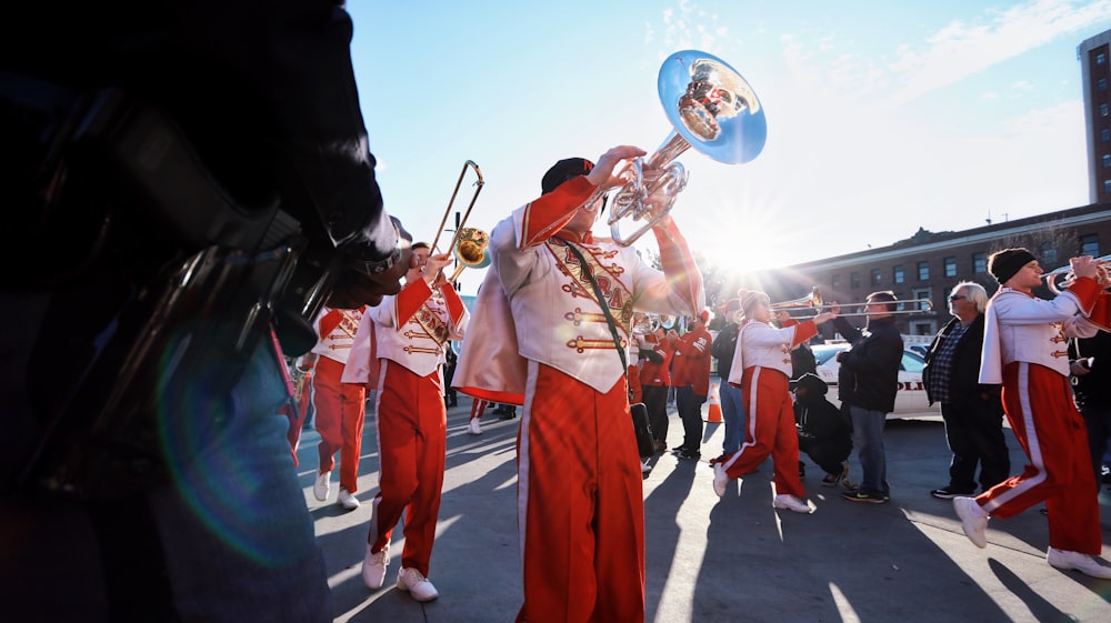 Personas con uniforme rojo y blanco tocando instrumentos musicales durante el día