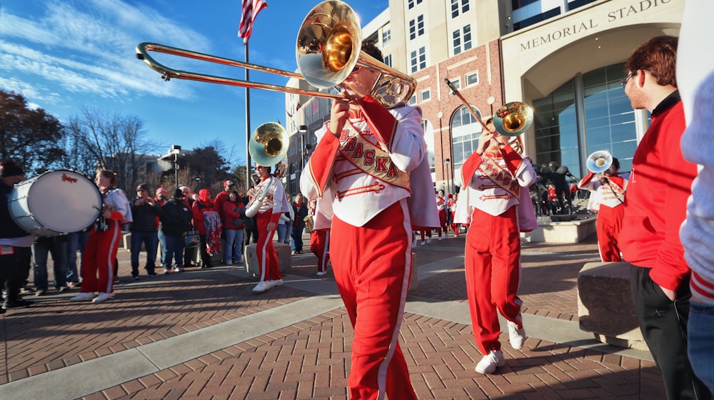 people in red and white uniform playing musical instruments on street during daytime