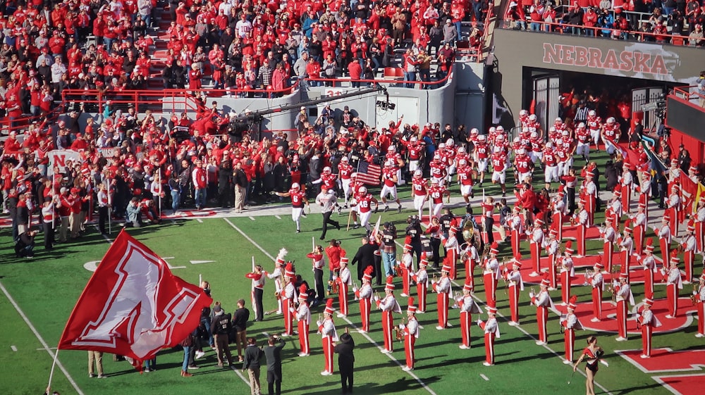 people in green and red uniform on green grass field during daytime