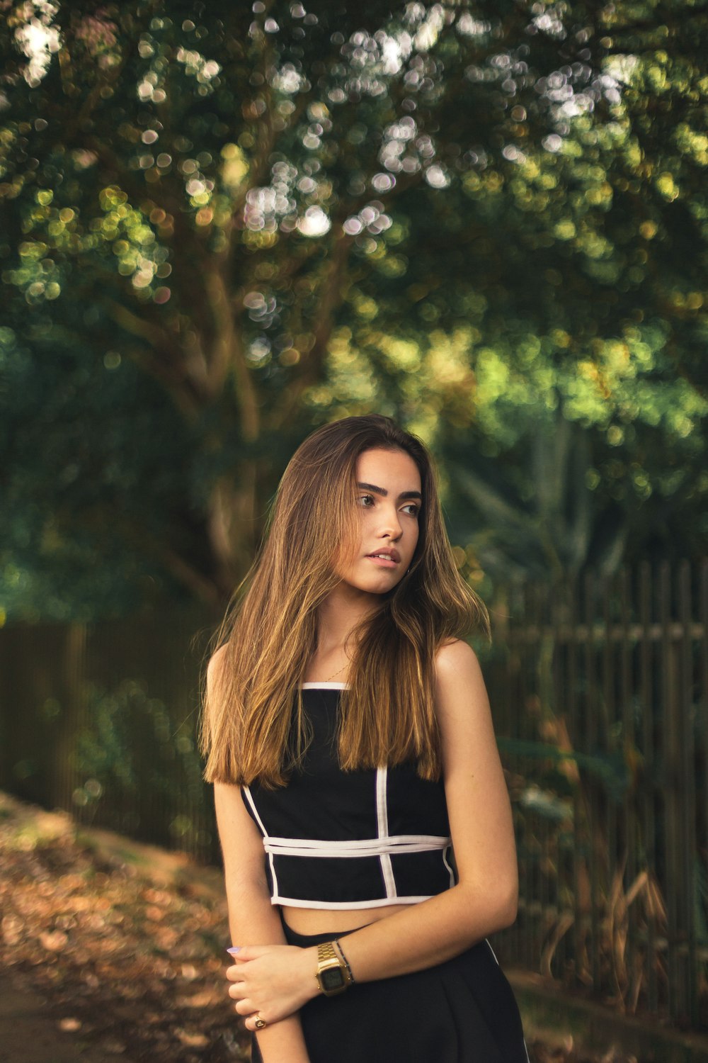 woman in black and white spaghetti strap top standing near green trees during daytime