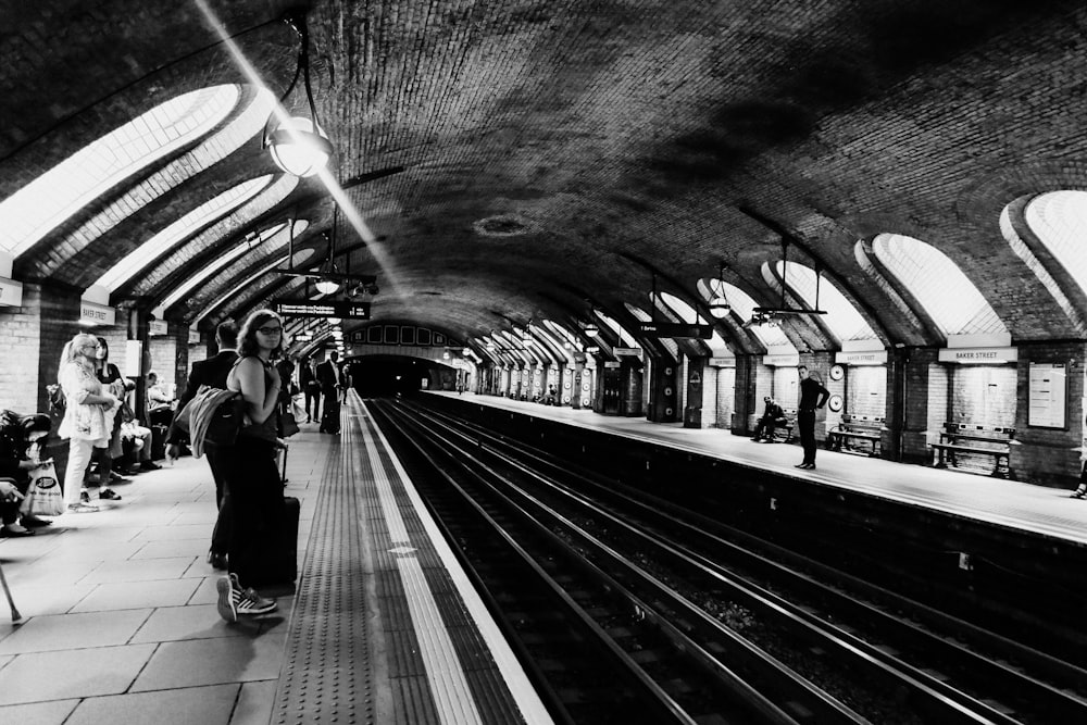 grayscale photo of people walking on train station