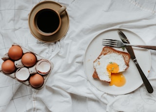 egg on white ceramic plate beside stainless steel fork and knife