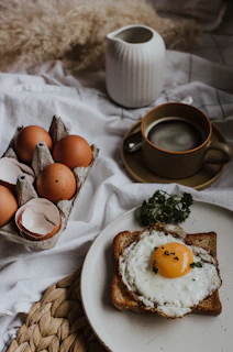 three eggs on white ceramic plate beside brown ceramic mug