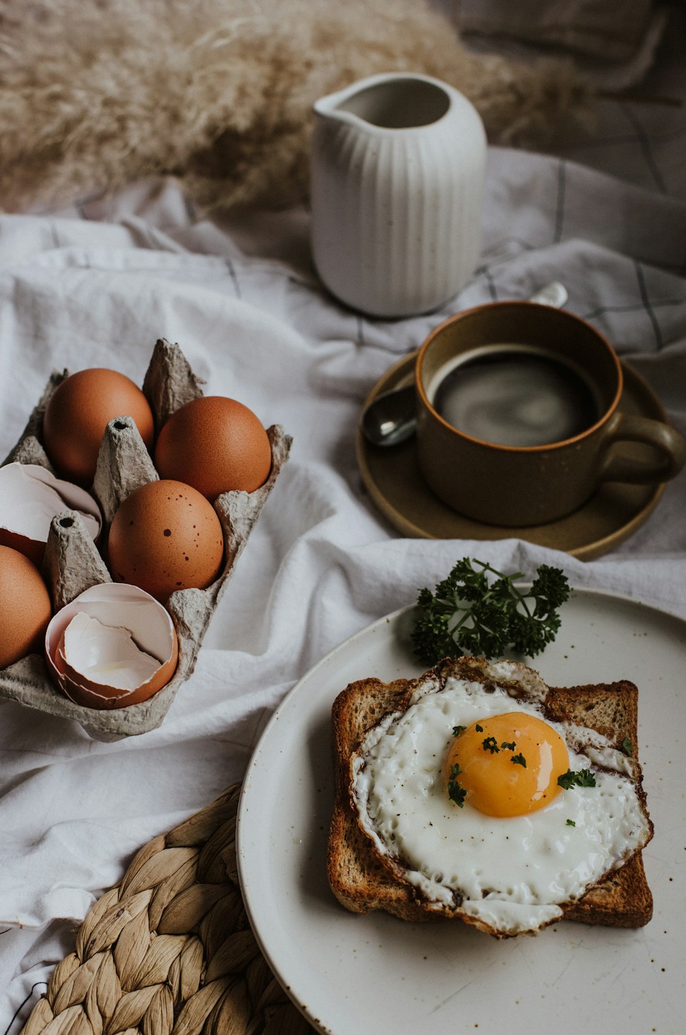 tres huevos en un plato de cerámica blanca junto a una taza de cerámica marrón