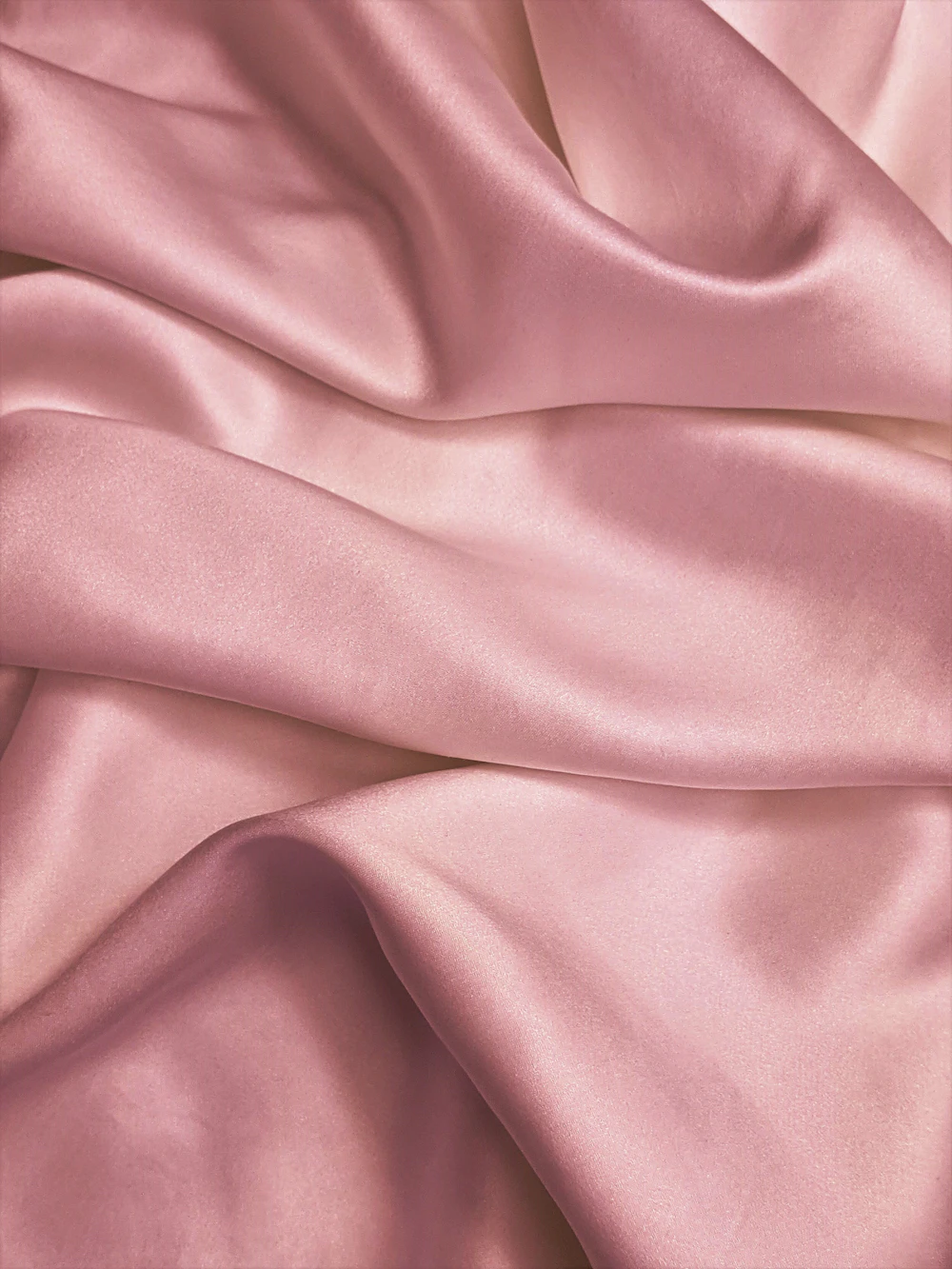 Blush pink silk draped in soft satin folds with a quiet sheen