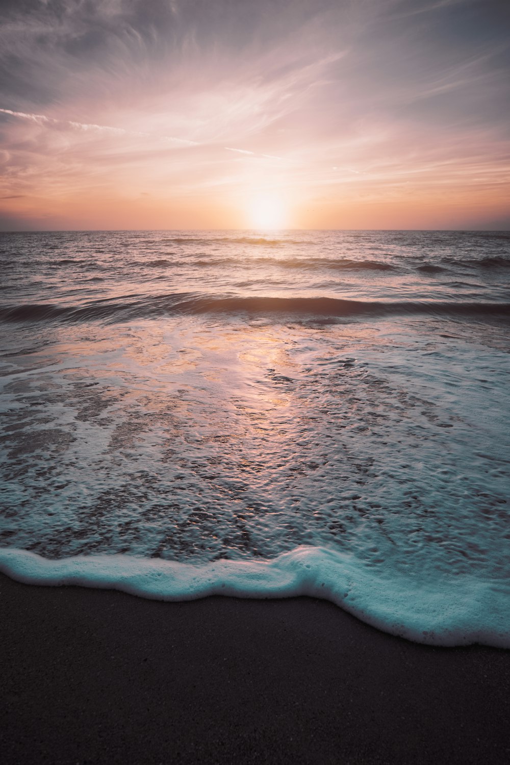 ocean waves crashing on shore during sunset