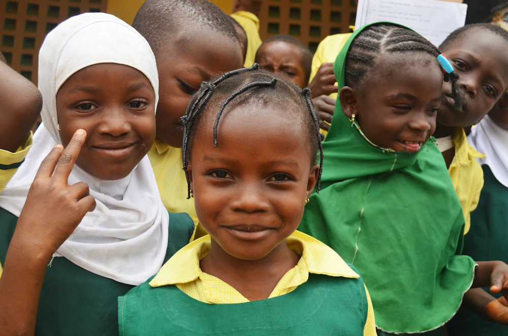 Élèves souriants en uniforme vert et blanc dans la cour de leur école