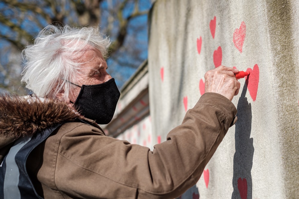 man in brown jacket holding red paint on white wall