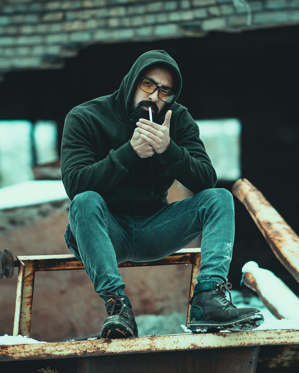 man in black long sleeve shirt and blue denim jeans sitting on brown wooden bench