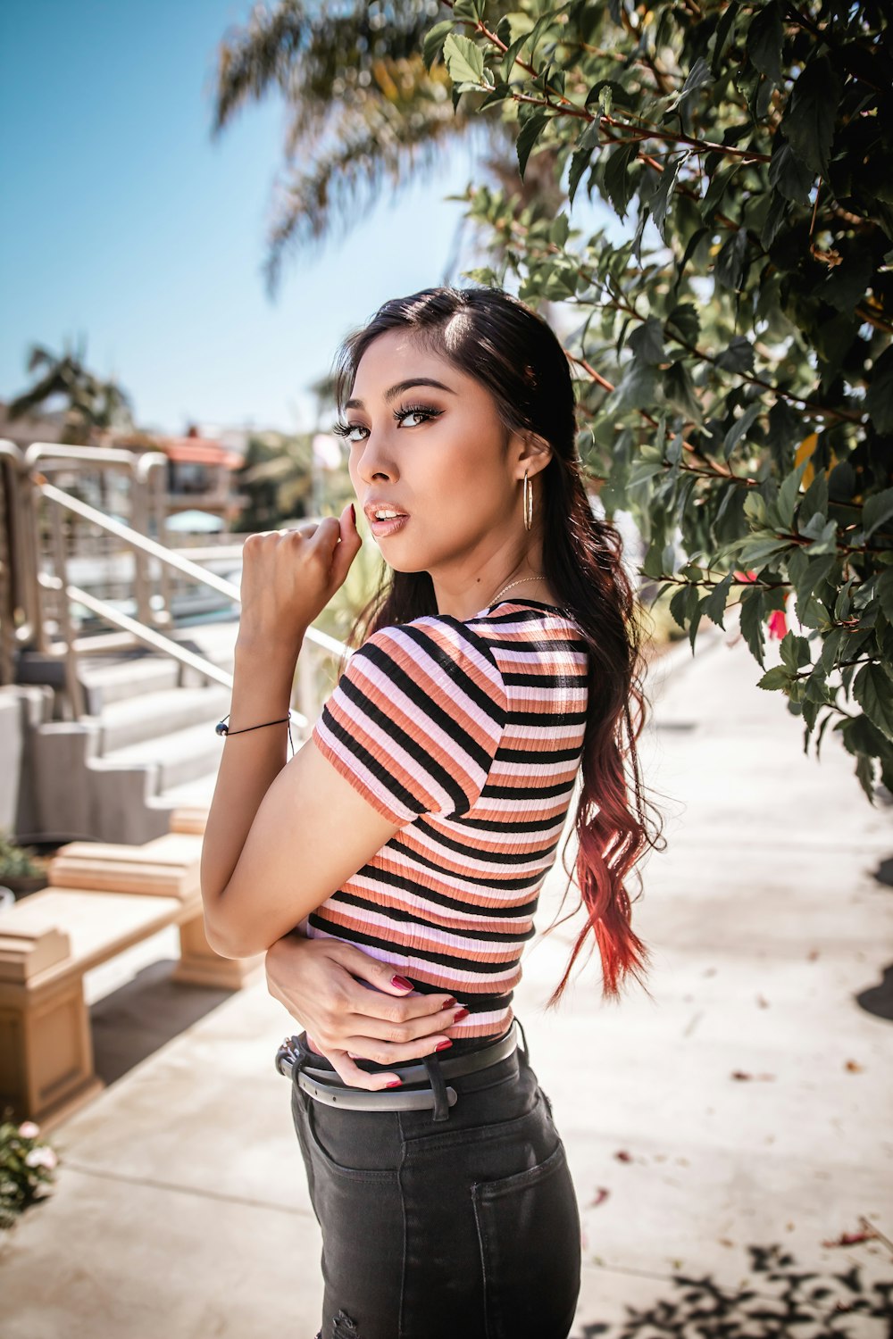 woman in red and white striped shirt and black denim shorts standing near green plants during