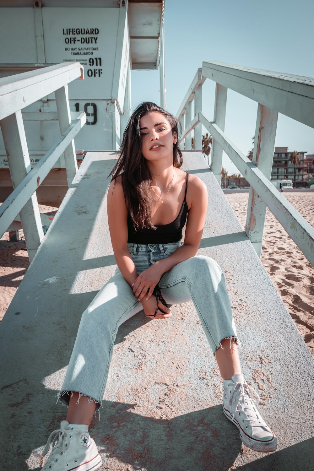 woman in black brassiere and blue denim jeans sitting on brown concrete stairs during daytime