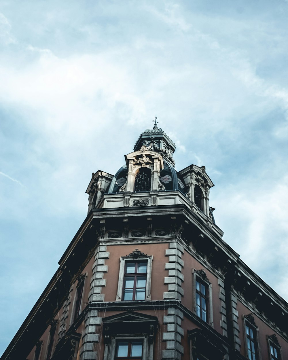 Braunes Betongebäude unter weißen Wolken tagsüber