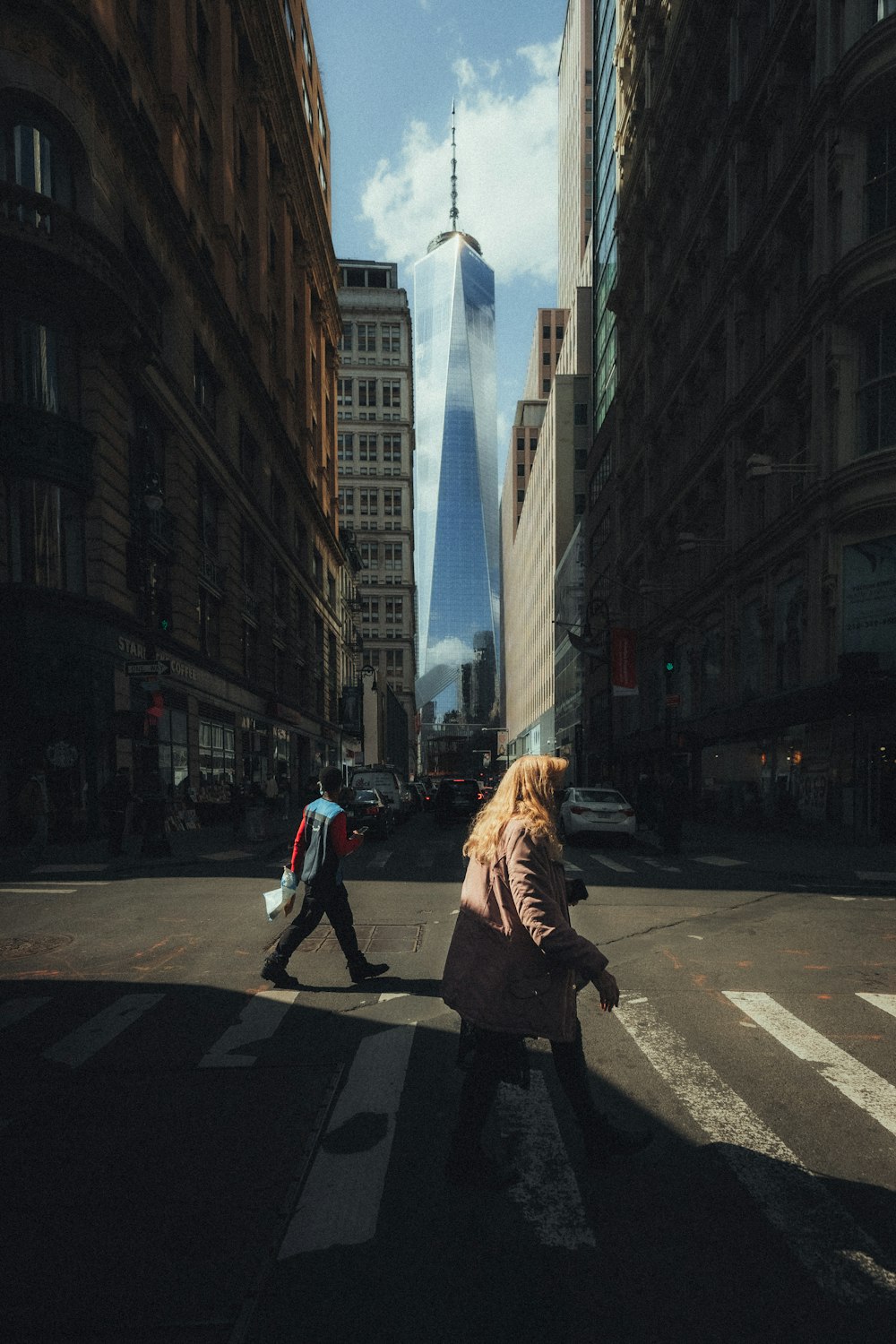 woman in black coat walking on sidewalk during daytime