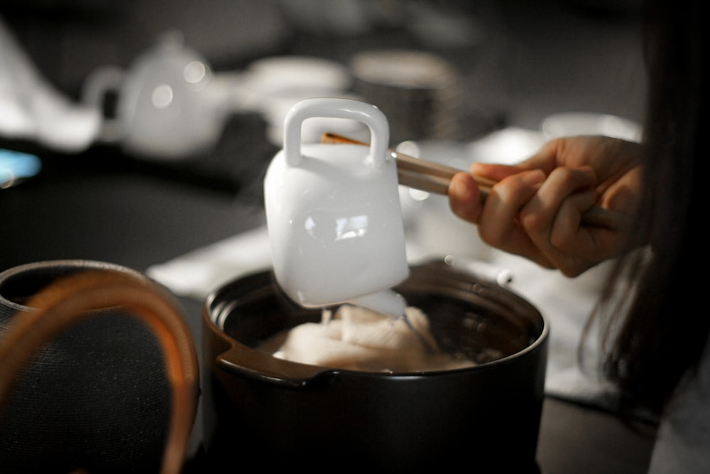 person holding white plastic container with white powder