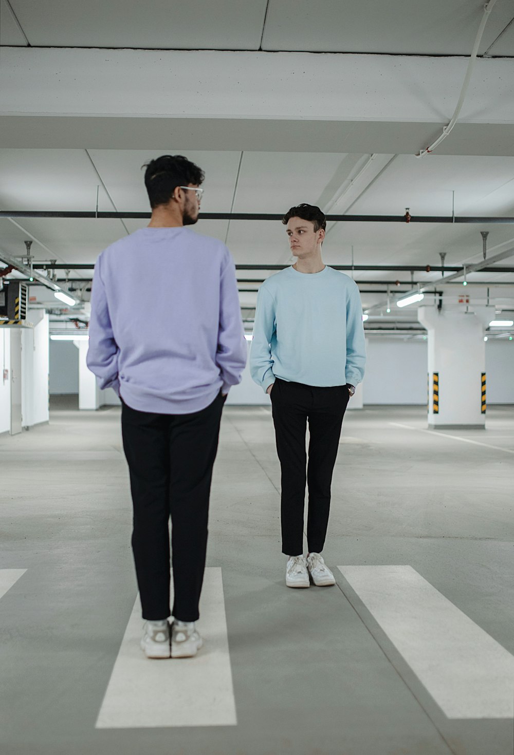 man in blue dress shirt and black pants standing on white floor