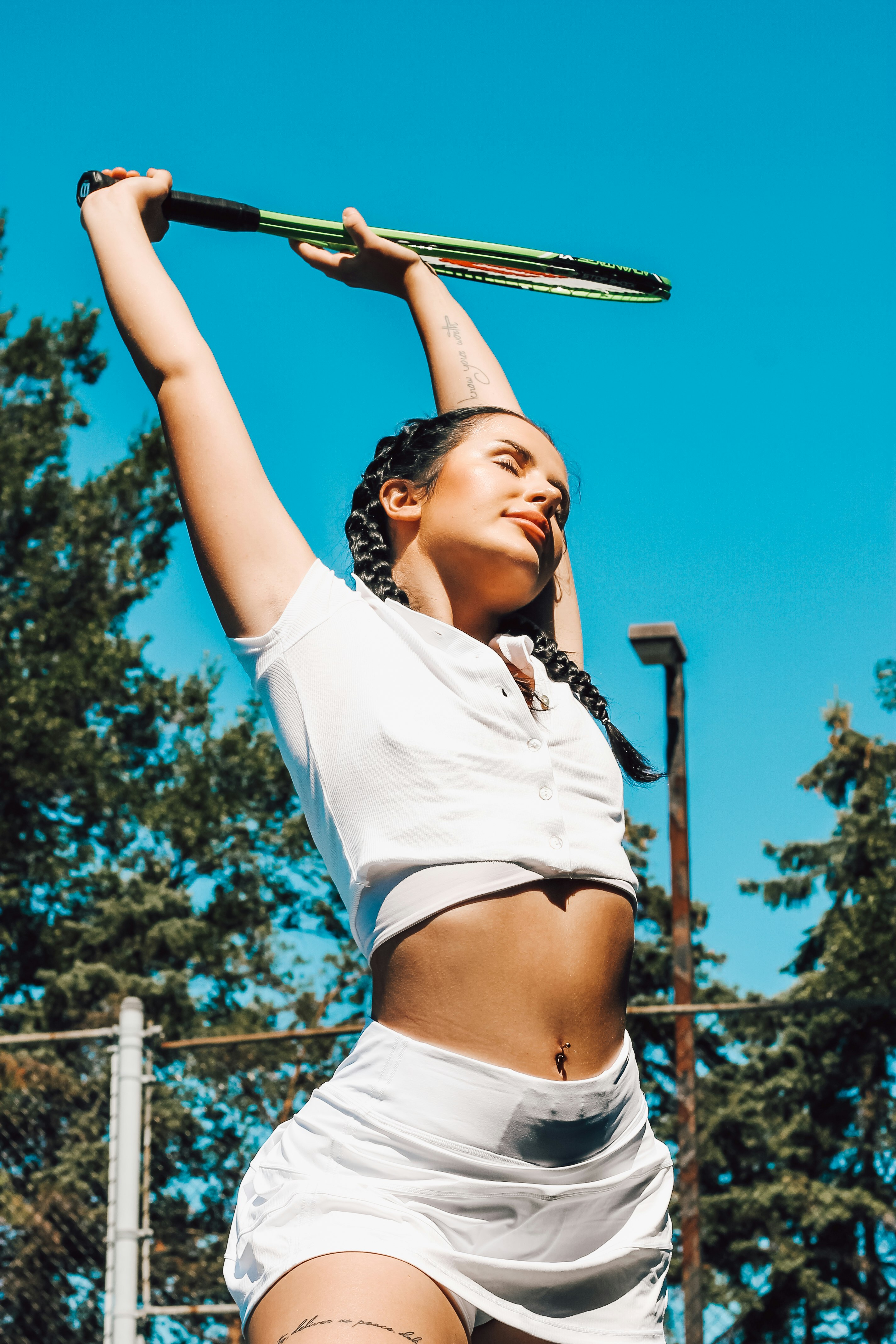 woman in white crop top and white shorts holding skateboard