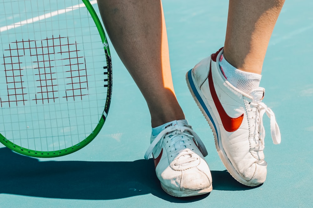 person wearing white and red nike athletic shoes