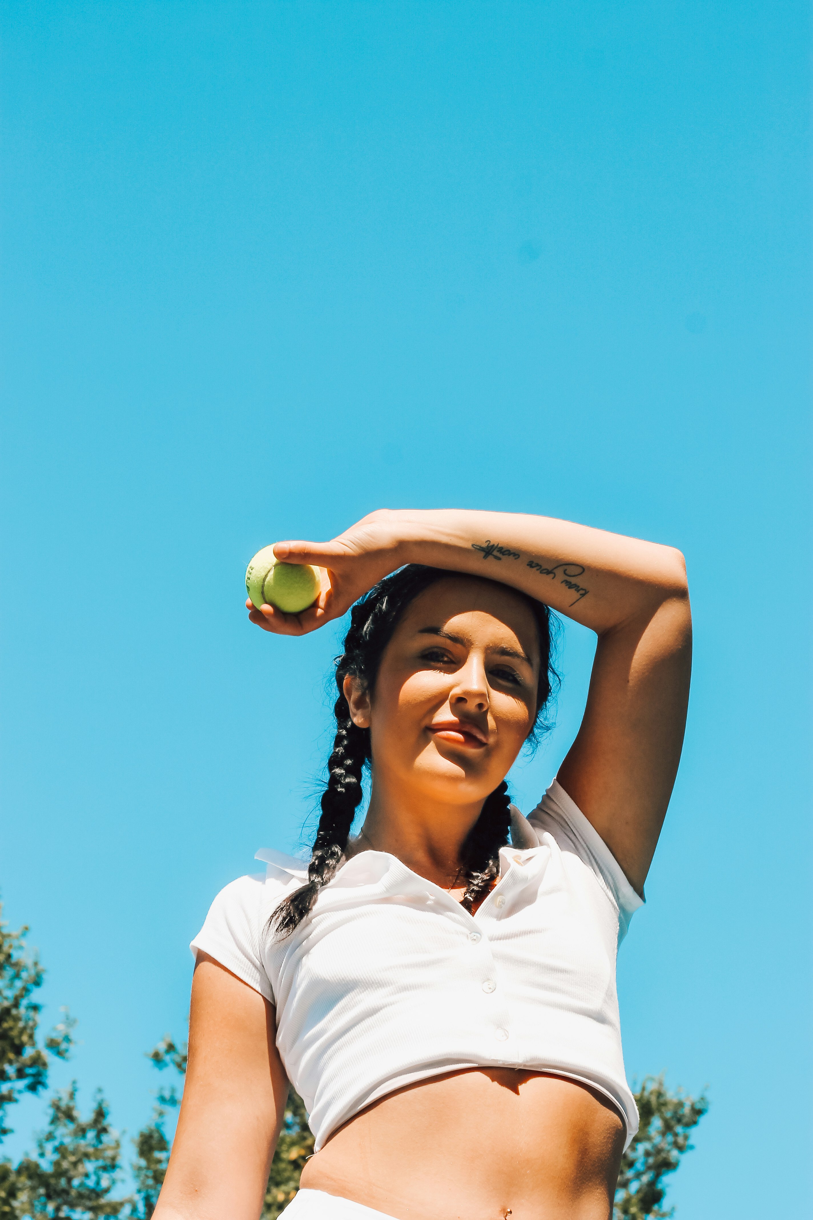 woman in white polo shirt holding green tennis ball