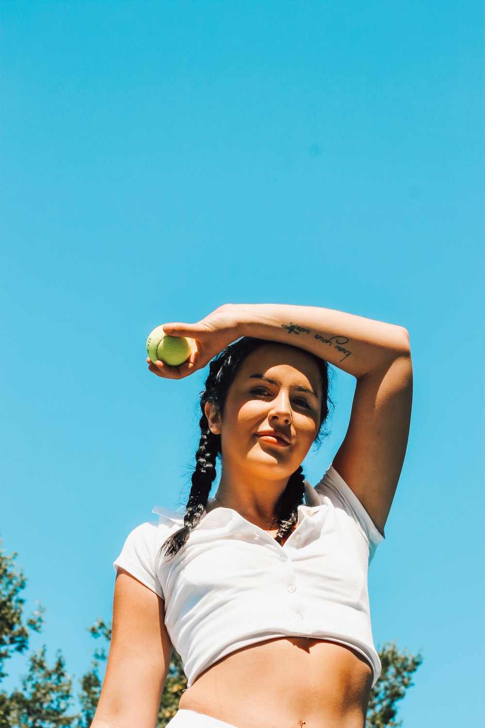 Mujer con polo blanco sosteniendo una pelota de tenis verde