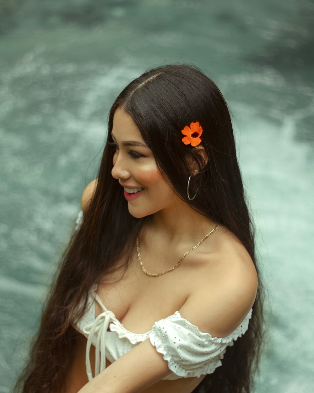 woman in white off shoulder shirt with white flower on her ear