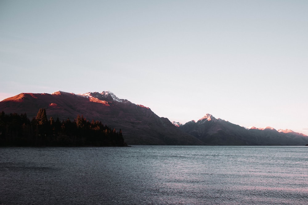 body of water near mountain during daytime