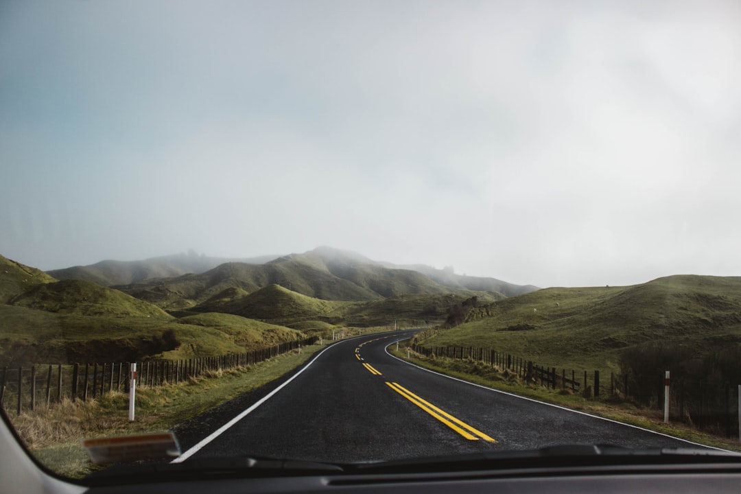 gray concrete road near green mountain during daytime