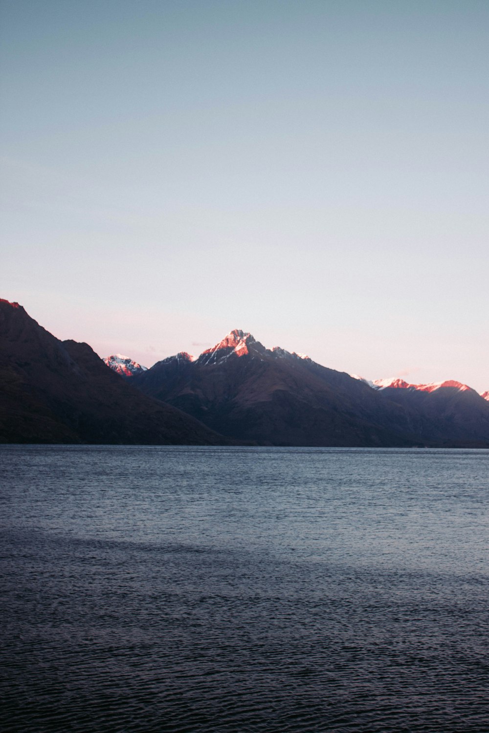 body of water near mountain during daytime