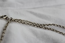 silver chain link necklace on white textile