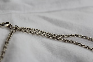 silver chain link necklace on white textile