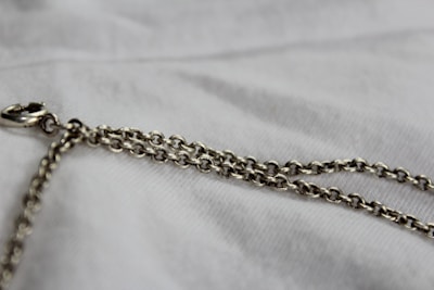 silver chain link necklace on white textile