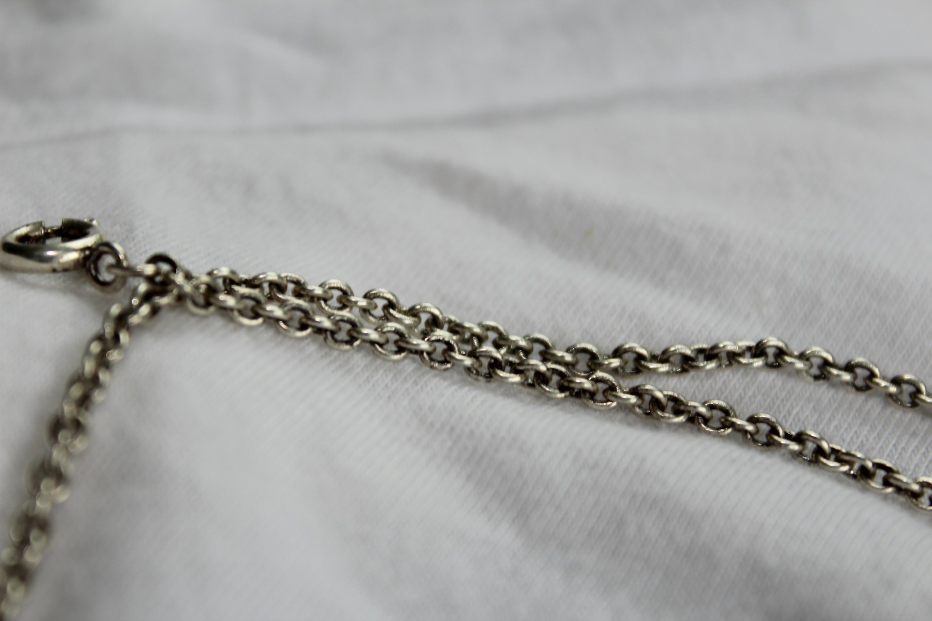 silver chain link necklace on white textile