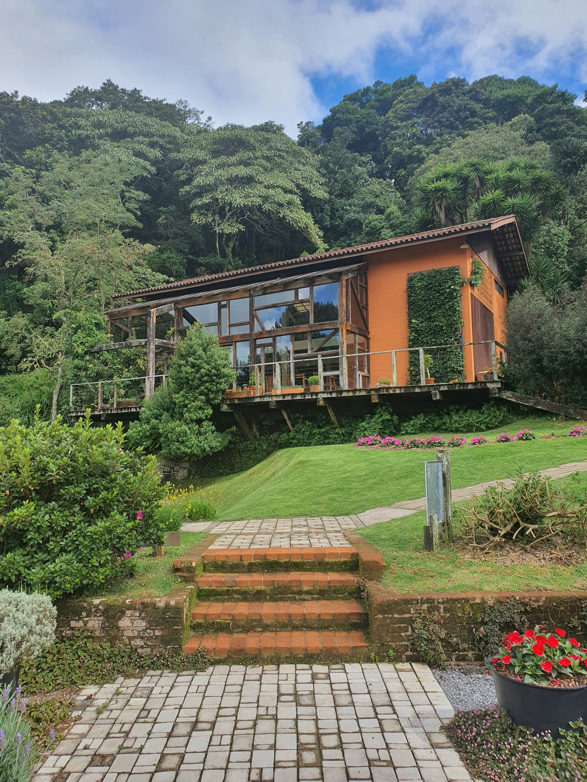 A stunning modern luxury home with expansive glass walls and warm wooden accents, nestled in a lush green landscape.