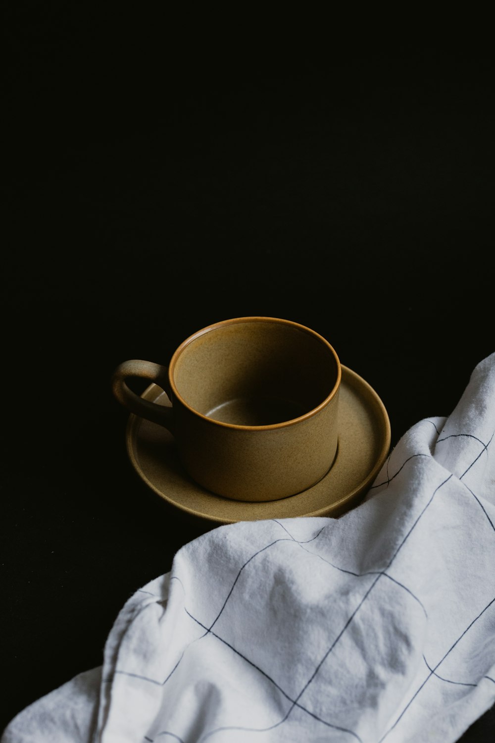 white ceramic mug on white textile