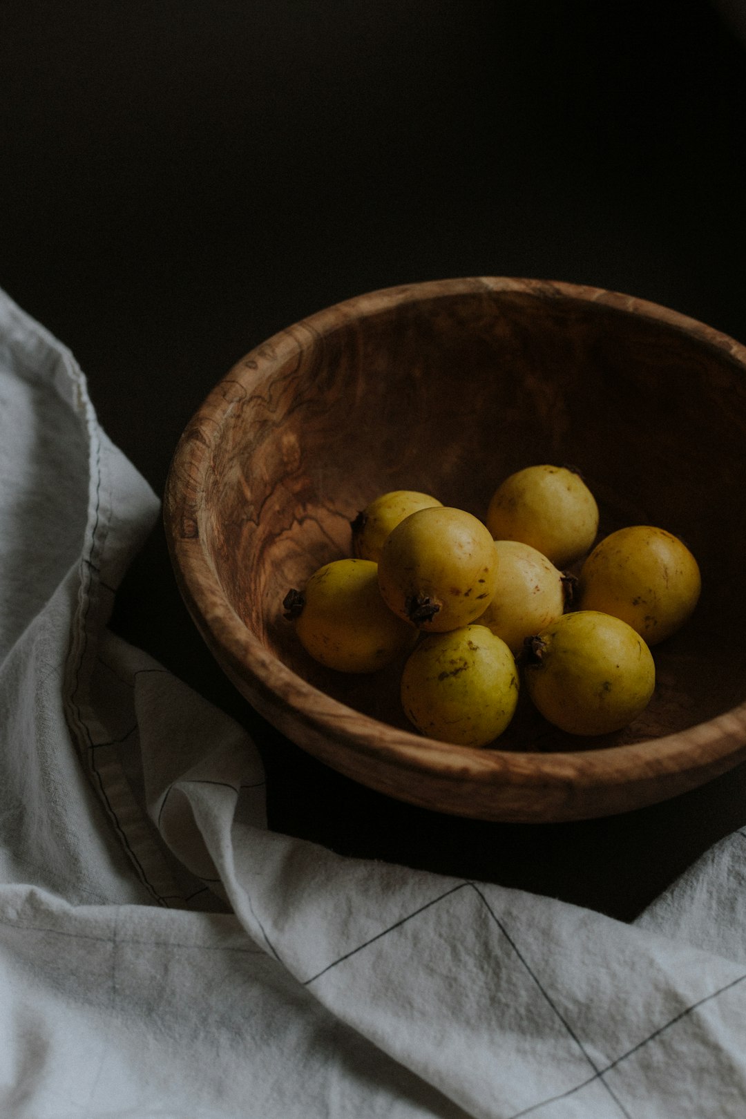 yellow round fruits in brown wooden bowl