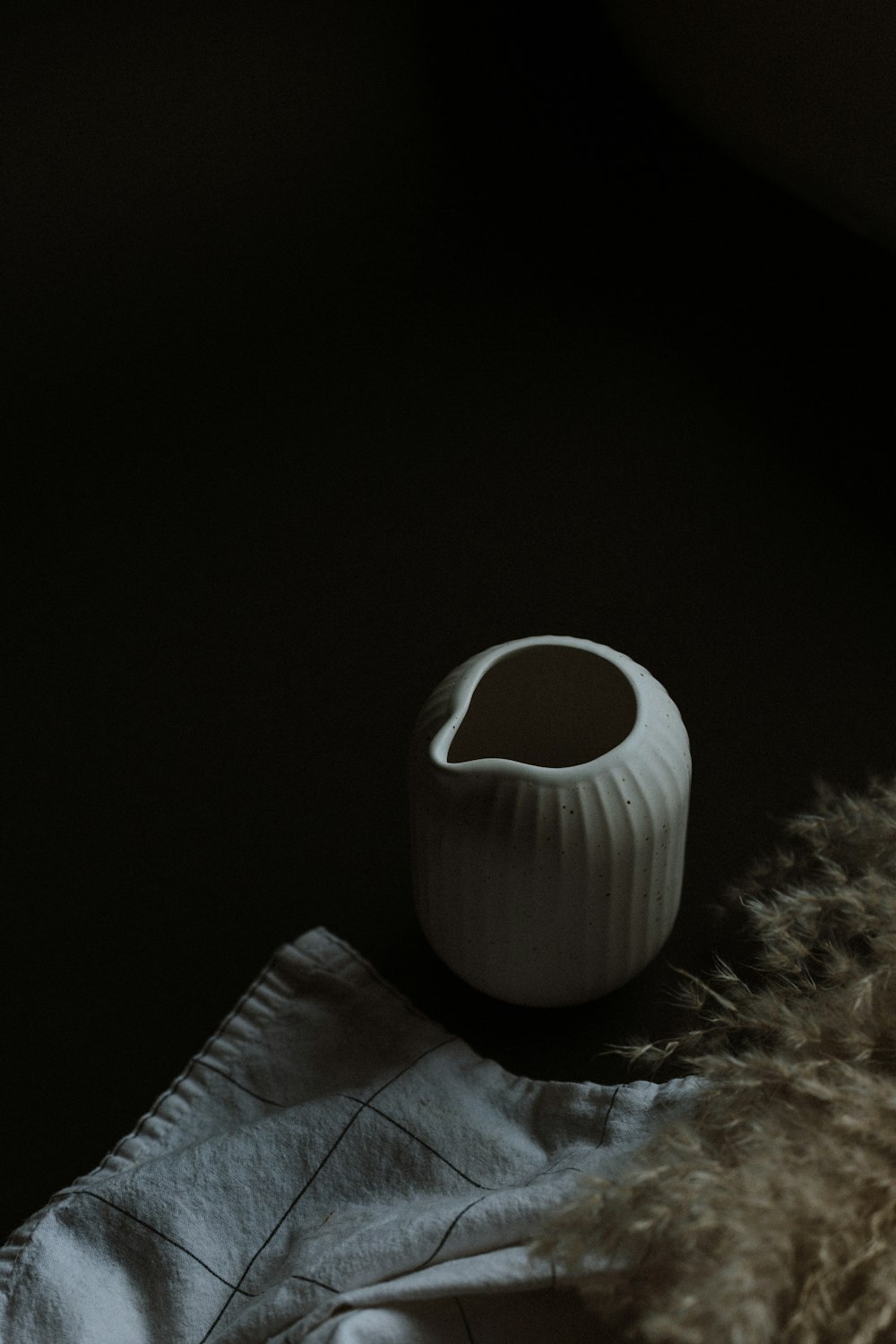 white ceramic mug on white textile