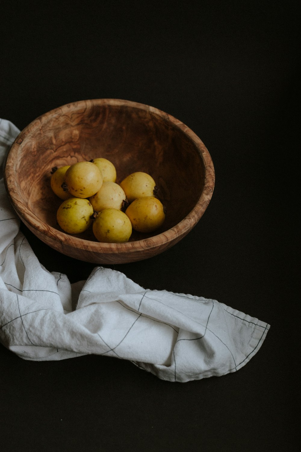 yellow round fruits on brown wooden bowl