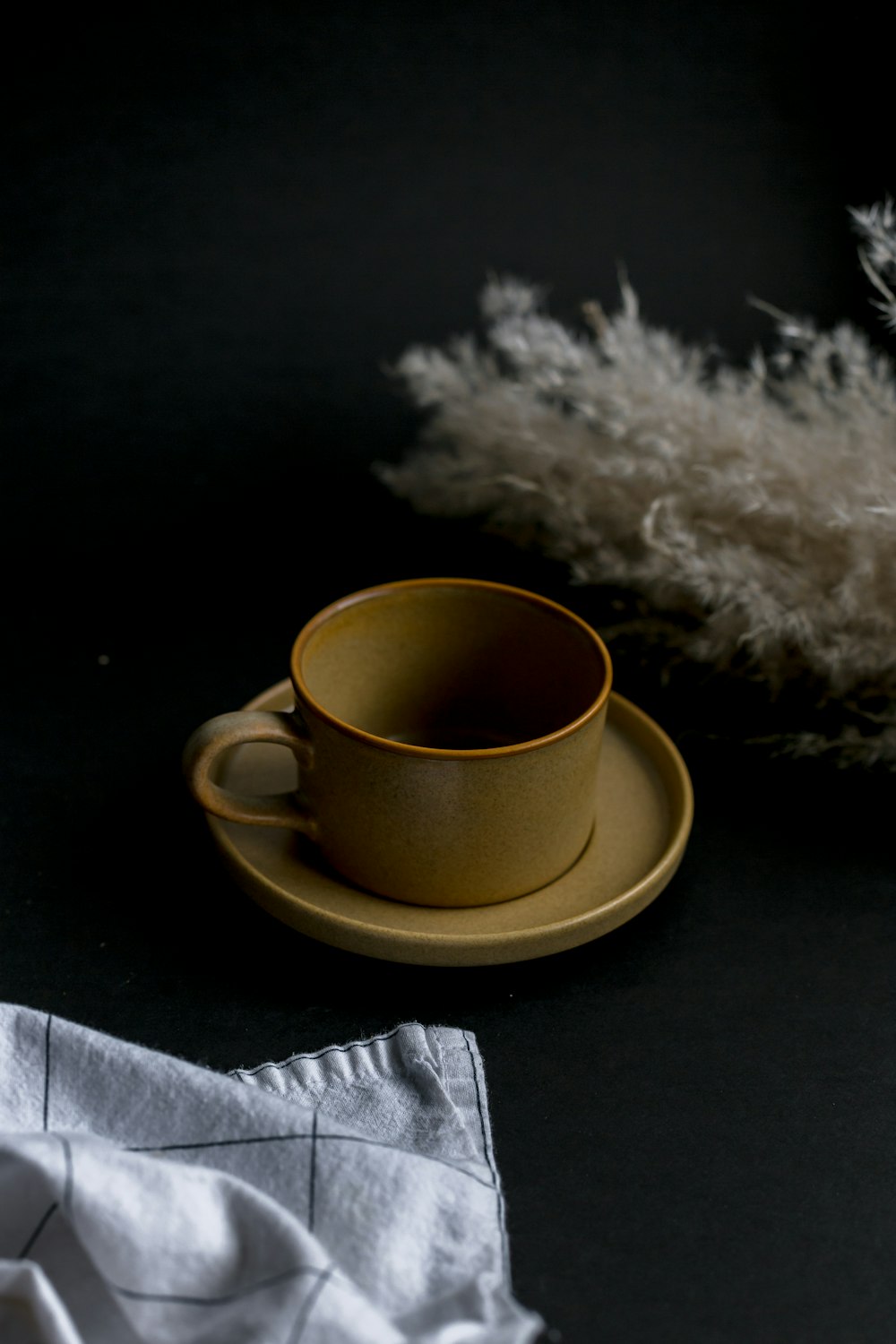 yellow ceramic mug on white textile