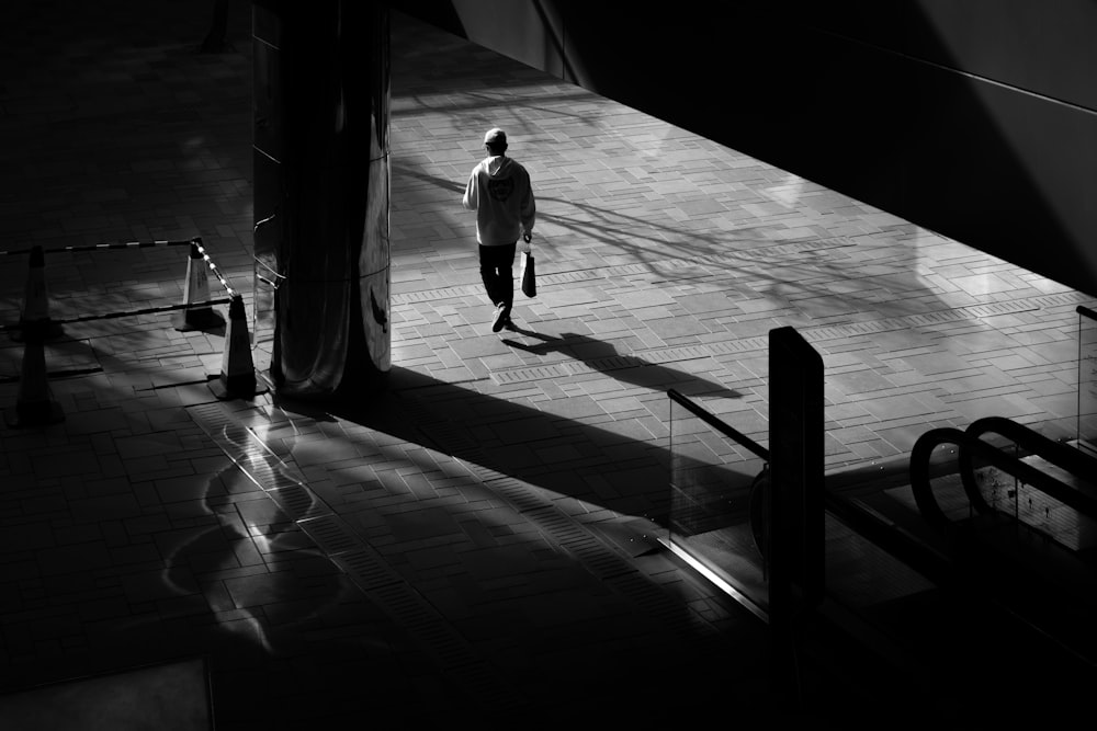 grayscale photo of man and woman walking on hallway
