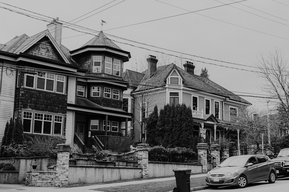 grayscale photo of car parked beside house